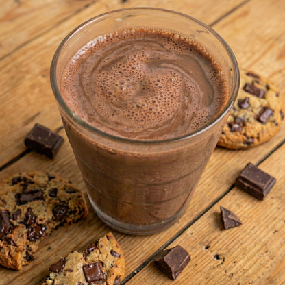 Milk chocolate shake in a clear glass with creamy texture and protein facts background